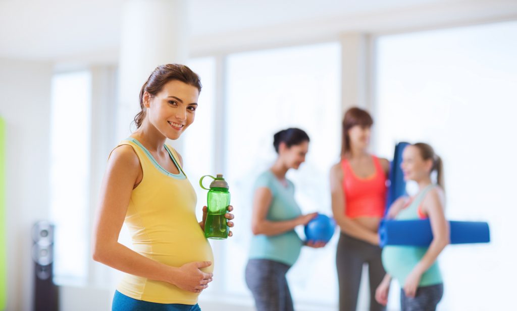 pregnancy, sport, fitness, people and healthy lifestyle concept - happy pregnant woman with water bottle in gym